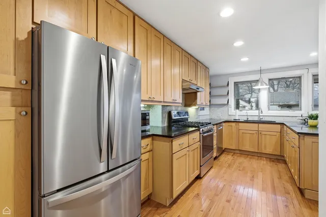 a kitchen with stainless steel appliances granite countertop a refrigerator a sink dishwasher a stove with large countertops and wooden floor