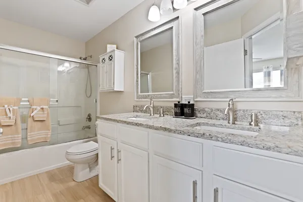 a bathroom with a granite countertop sink a toilet and a shower
