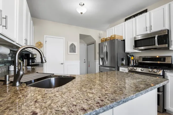 a kitchen with stainless steel appliances granite countertop a sink a stove and a refrigerator