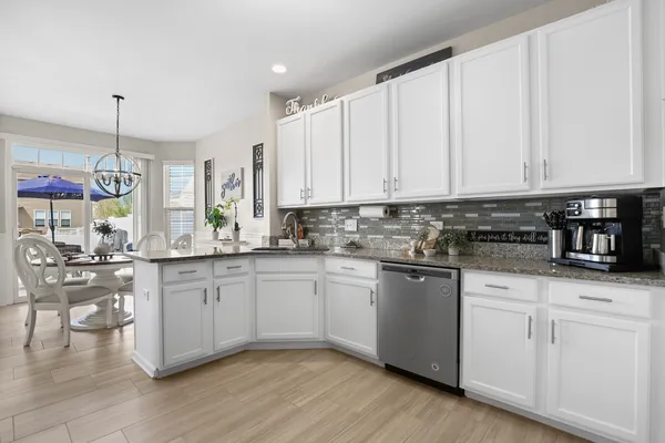 a kitchen with stainless steel appliances granite countertop a stove a sink and white cabinets