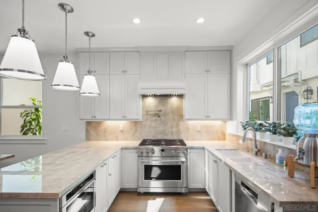 a kitchen with stainless steel appliances granite countertop a sink a stove and a wooden floors