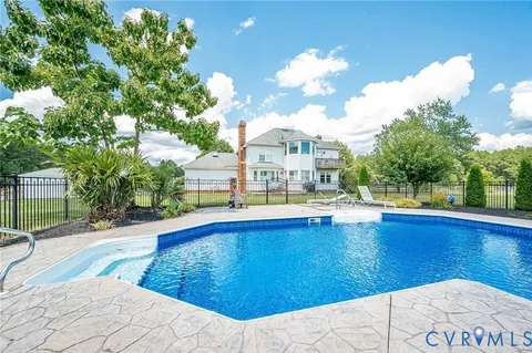 a view of swimming pool with outdoor seating and trees in the background