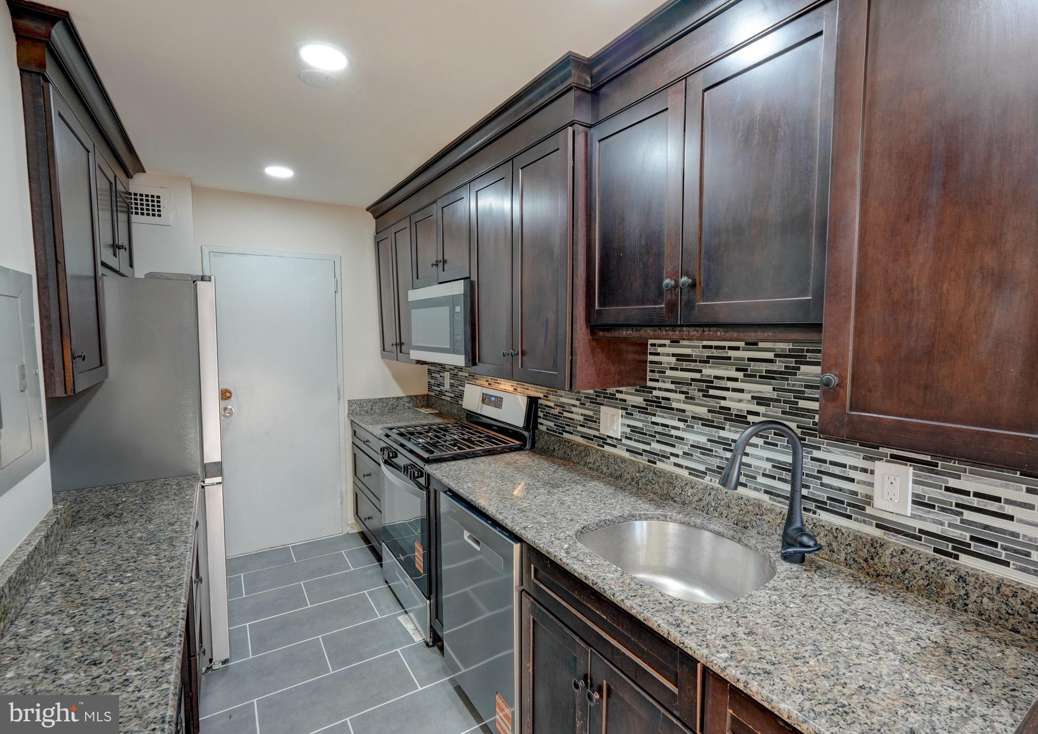 1900 Lyttonsville Road, Unit 211 Silver Spring, MD 20910 - Photo 12 of 46 a kitchen with granite countertop stainless steel appliances a sink stove and refrigerator