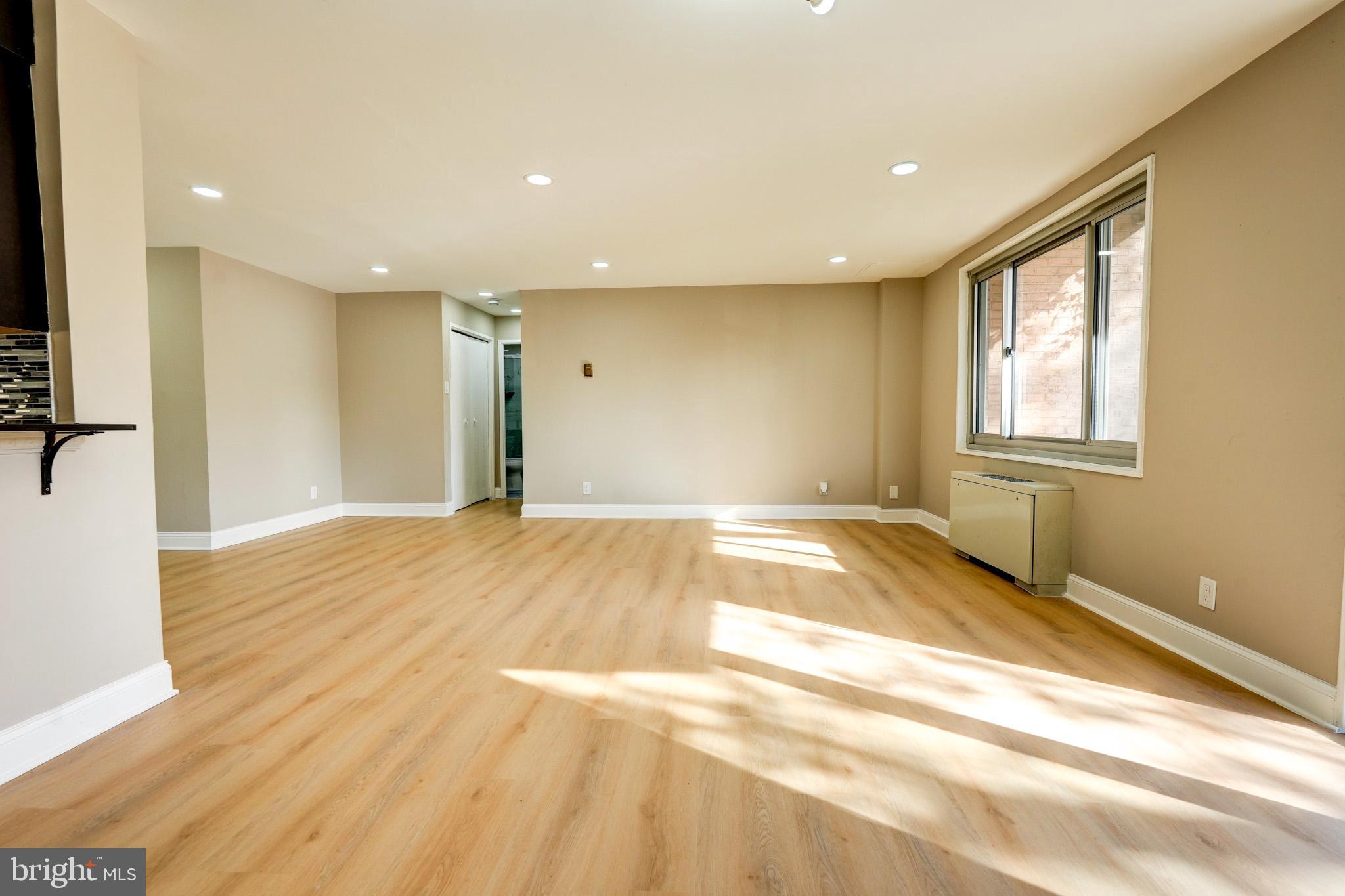 1900 Lyttonsville Road, Unit 211 Silver Spring, MD 20910 - Photo 6 of 46 a view of an empty room with wooden floor and a window