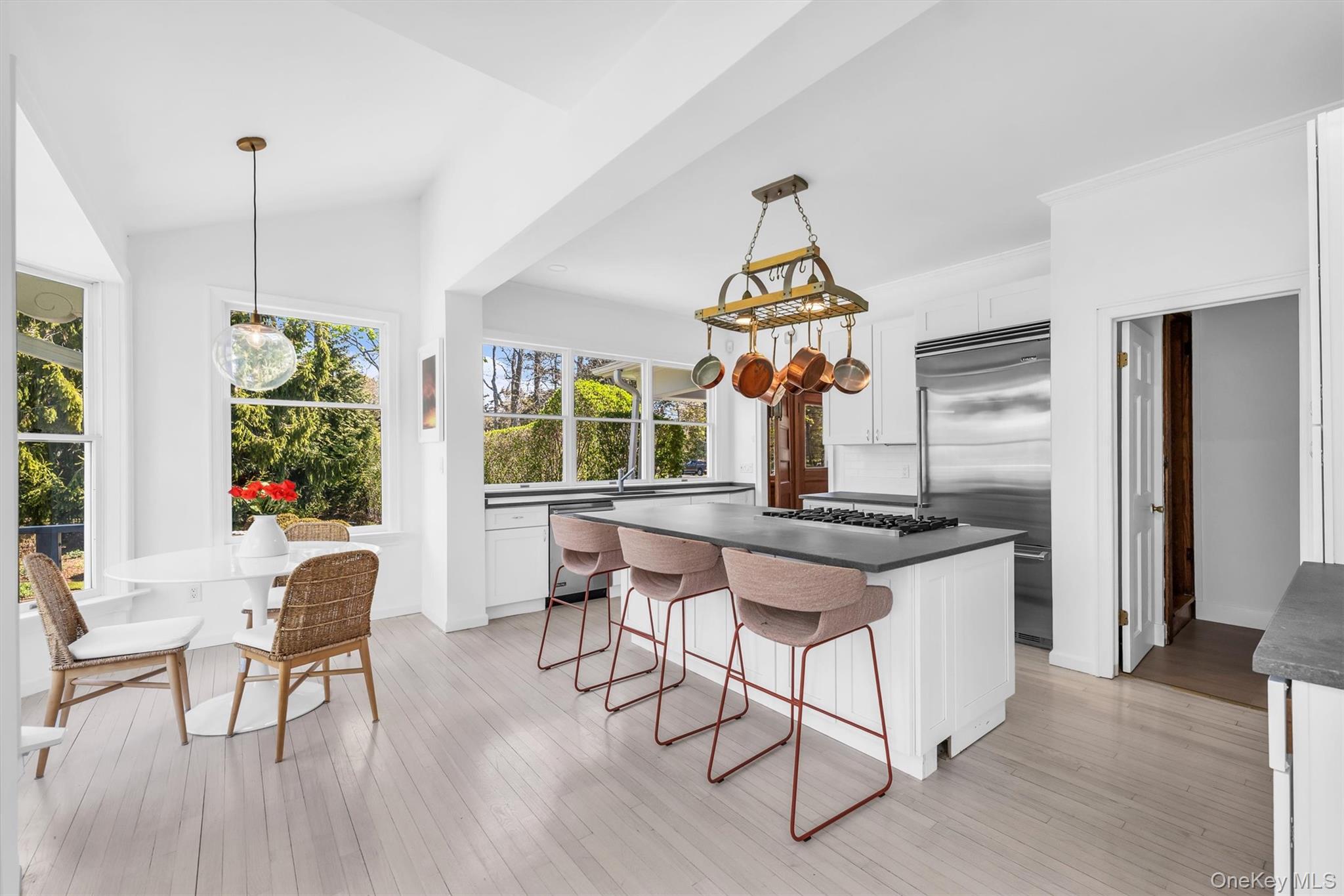 64 South Howells Point Road Bellport, NY 11713 - Photo 8 of 42 a kitchen with stainless steel appliances granite countertop a stove a sink dishwasher a dining table and chairs with wooden floor