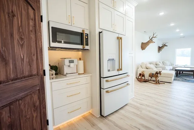 a kitchen with stainless steel appliances granite countertop a table chairs sink and cabinets