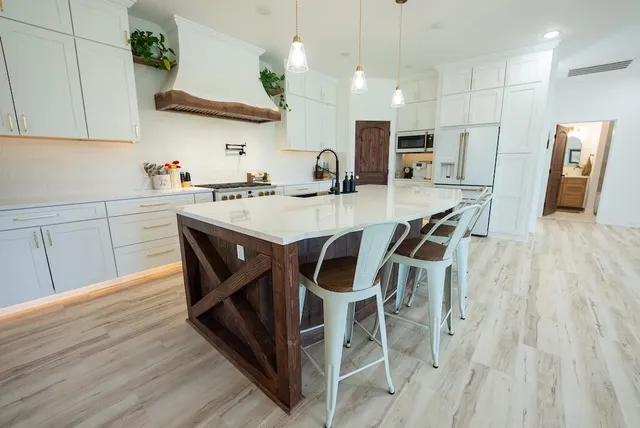 a kitchen with stainless steel appliances granite countertop a sink and a stove top oven with wooden floor