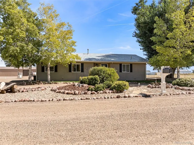 a front view of a house with a dirt yard and a large tree