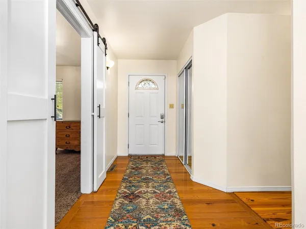 a view of a hallway with wooden floor and bathroom