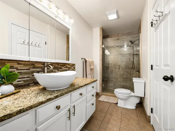 a bathroom with a granite countertop sink mirror and toilet