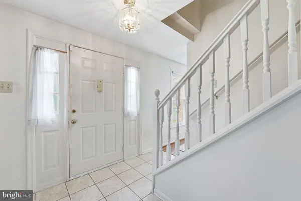 a view of staircase with white walls and chandelier