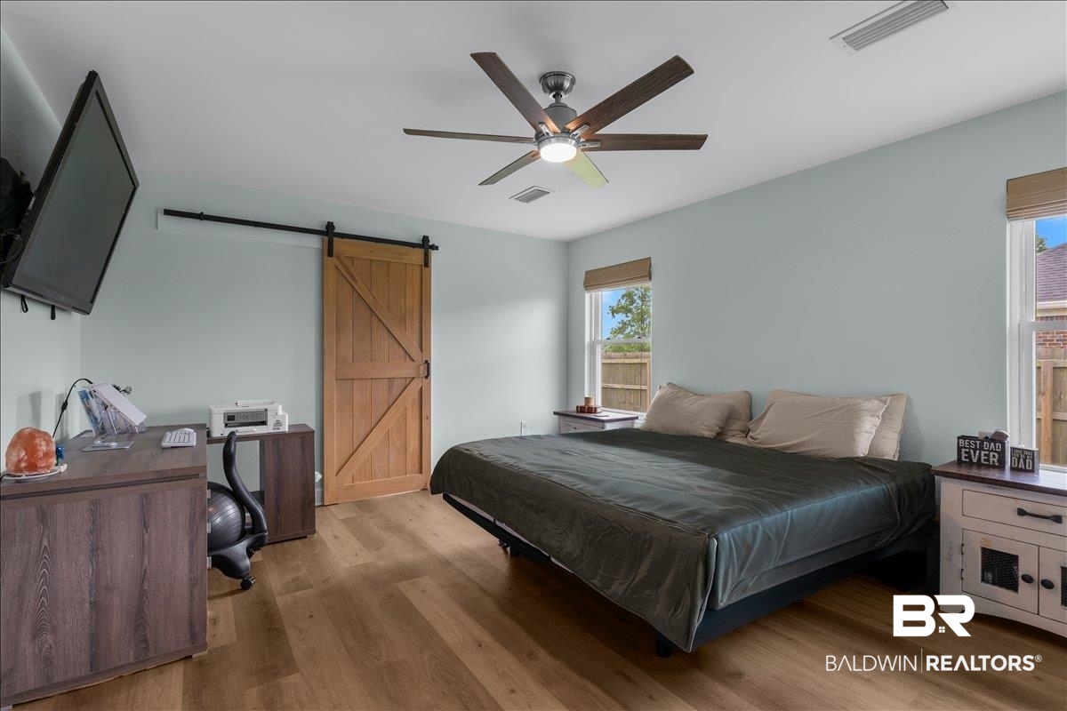 8952 Sherman Road Foley, AL 36535 - Photo 24 of 41 Spacious room featuring wood-finish flooring, a contemporary ceiling fan with integrated lighting, and a barn door with black hardware