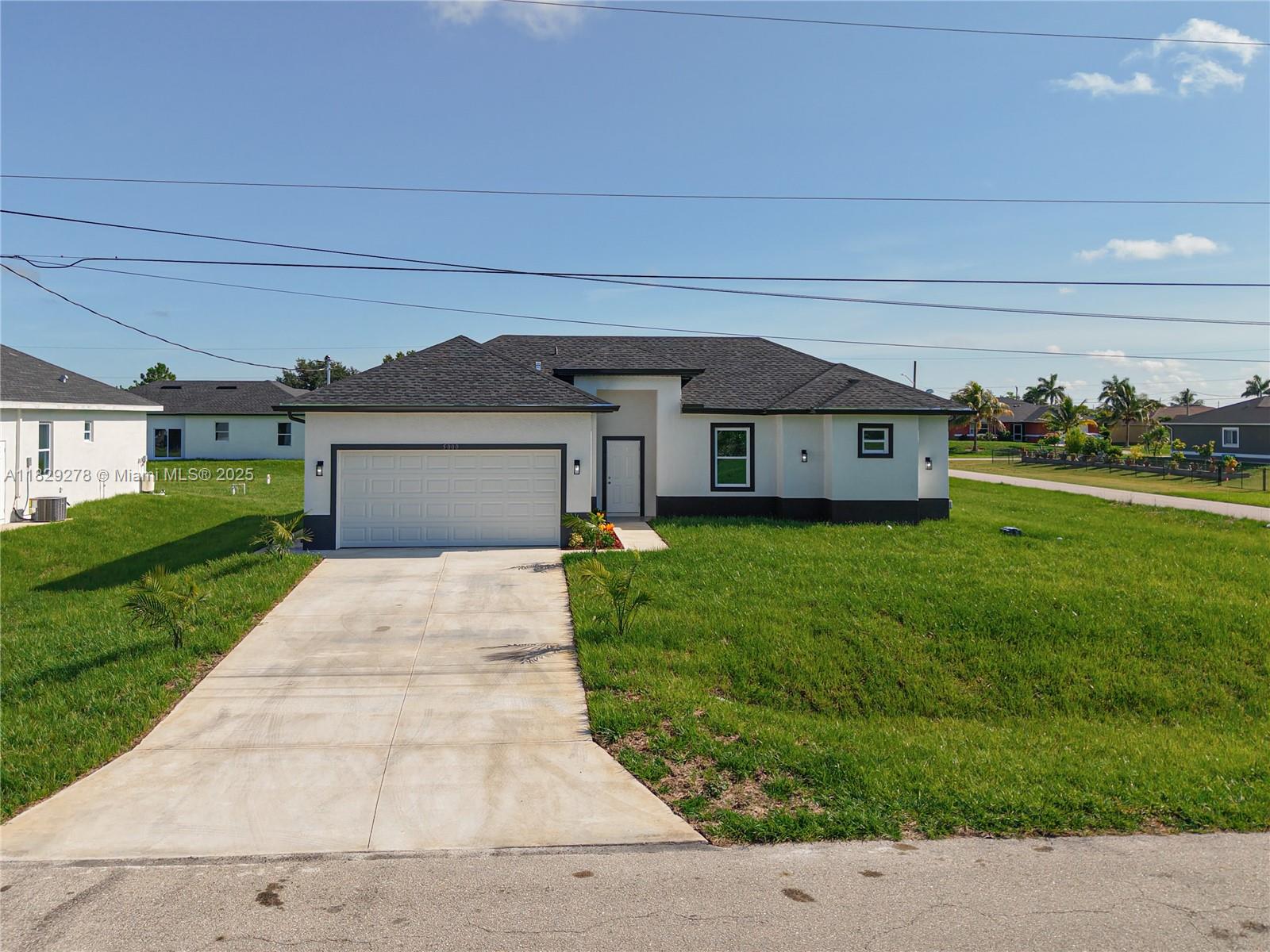 5002 Bygone Street Lehigh Acres, FL 33971 - Photo 2 of 51 a front view of a house with a yard and garage