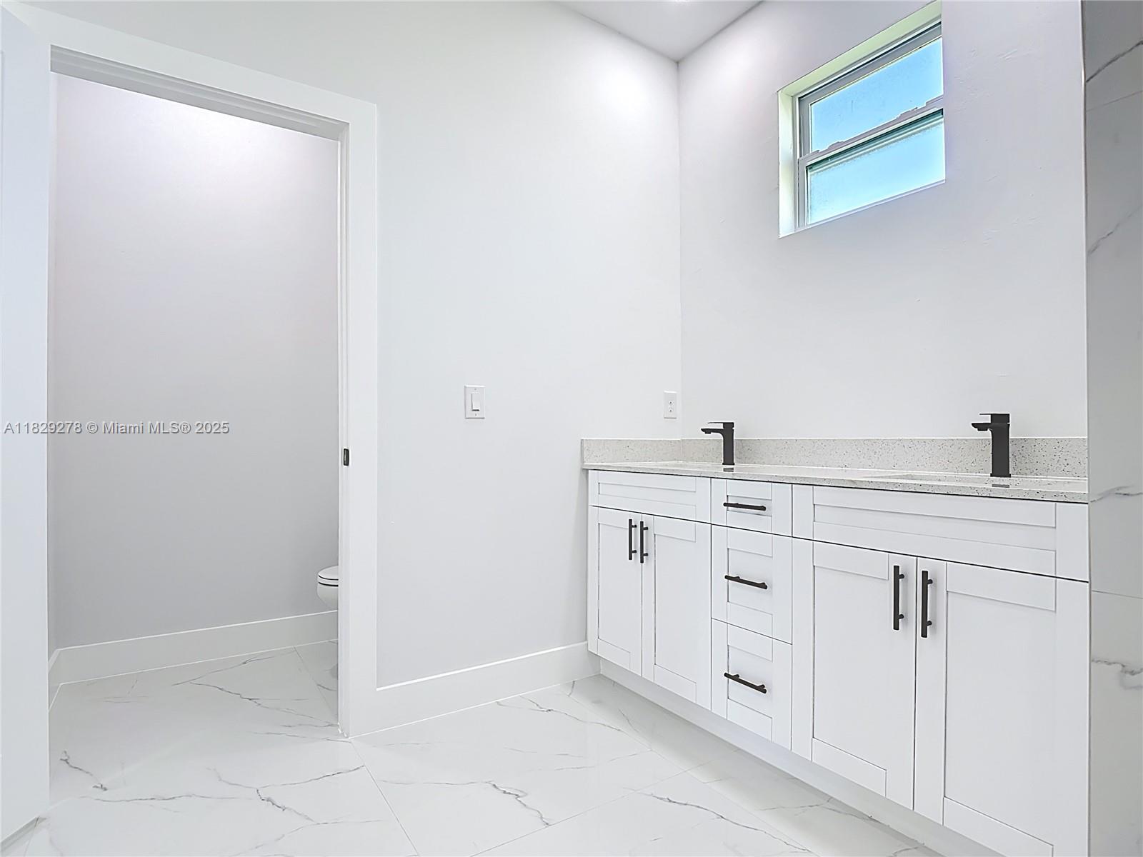 5002 Bygone Street Lehigh Acres, FL 33971 - Photo 37 of 51 a spacious bathroom with a double vanity sink a mirror and shower
