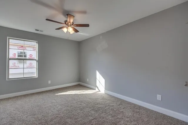 an empty room with wooden floor and ceiling fan