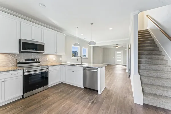 a kitchen with kitchen island granite countertop a sink cabinets and stainless steel appliances