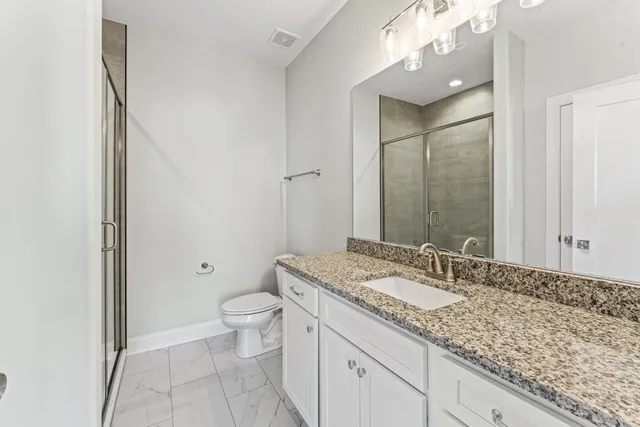 a bathroom with a granite countertop sink a toilet and a mirror