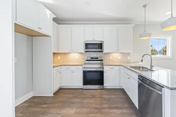 a kitchen with granite countertop a stove top oven a sink dishwasher and a refrigerator with wooden floor