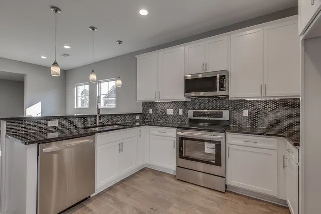 a kitchen with stainless steel appliances granite countertop a stove and a microwave
