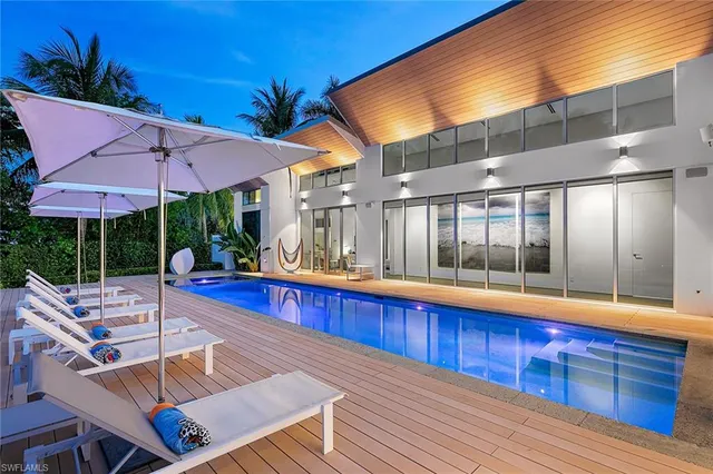 a view of a patio with couches table and chairs with wooden floor and fence
