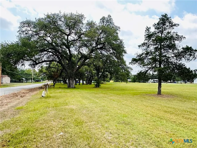 a swimming pool with a yard and trees in the background