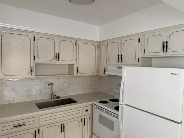 a kitchen with white cabinets and white appliances