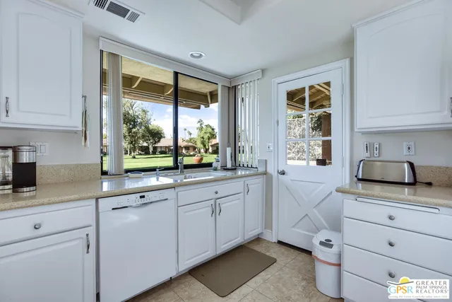 a kitchen with white cabinets and window