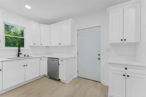 a kitchen with white cabinets and sink