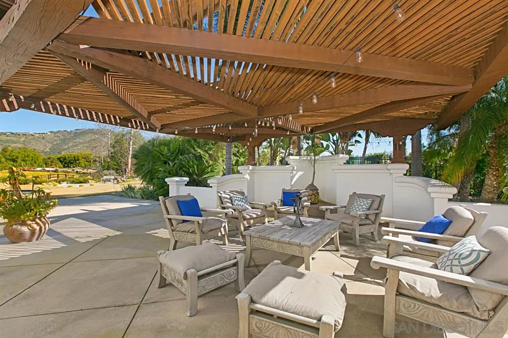 7152 Rancho La Cima Drive Rancho Santa Fe, CA 92067 - Photo 23 of 25 a patio with a patio table and chairs with swimming pool