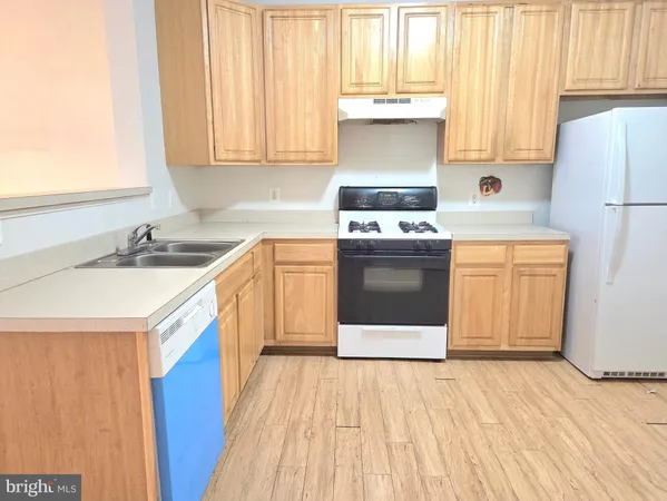 a kitchen with stainless steel appliances a stove a sink and white cabinets with wooden floor