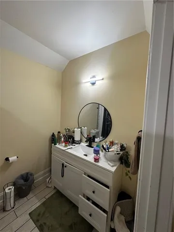 a view of an empty room with wooden floor and a kitchen