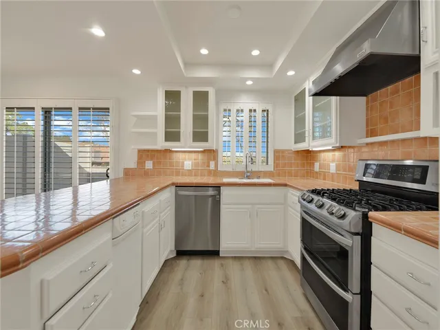 a kitchen with granite countertop stainless steel appliances a stove sink and cabinets