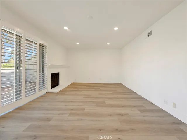 a view of empty room with wooden floor and fireplace