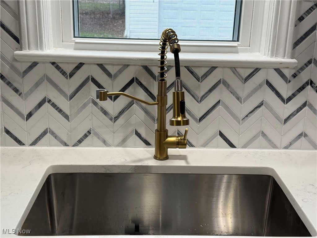 6807 Gerald Avenue Parma, OH 44129 - Photo 9 of 25 Interior details featuring a sink, decorative backsplash, and light stone countertops