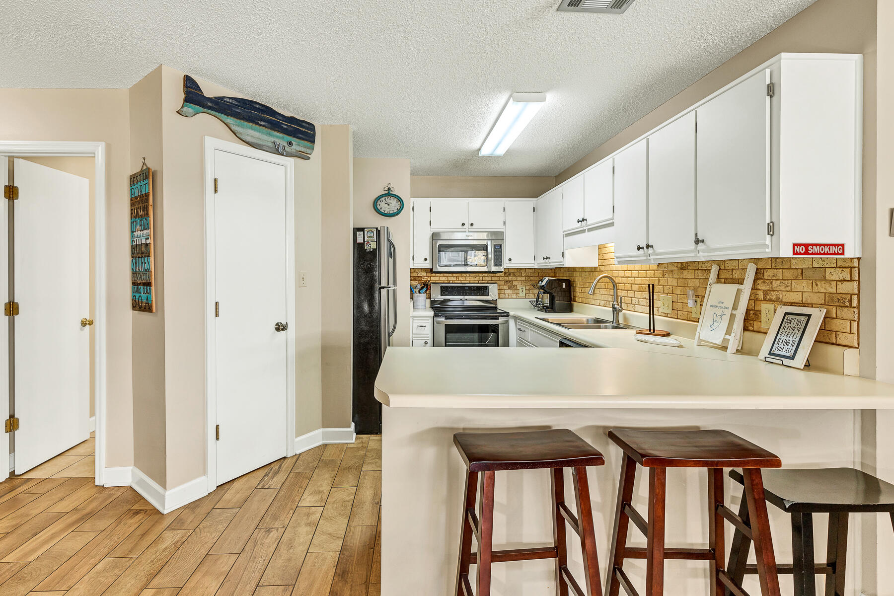 3799 East County Highway 30A, Unit D10 Santa Rosa Beach, FL 32459 - Photo 24 of 42 a kitchen with stainless steel appliances granite countertop a stove a refrigerator a sink and white cabinets with wooden floor