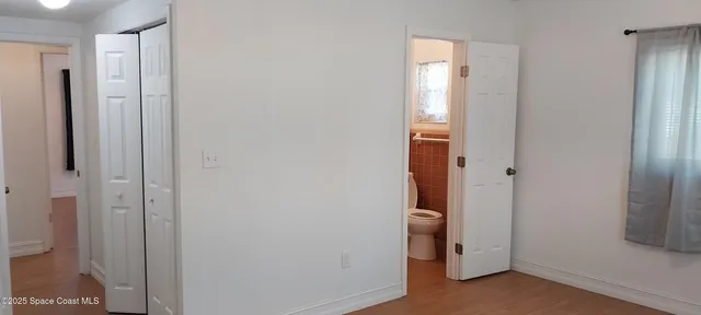 a view of an empty room with closet and mirror