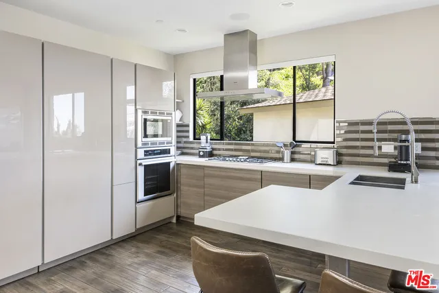 a kitchen with kitchen island a counter top space a sink stainless steel appliances and cabinets