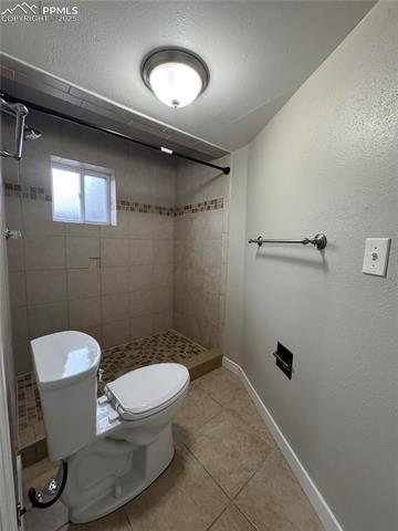 4420 Galley Road Colorado Springs, CO 80915 - Photo 20 of 20 Bathroom with toilet, a stall shower, baseboards, tile patterned floors, and a textured ceiling