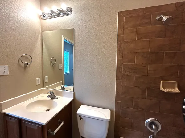 an empty room with wooden floor and way to kitchen