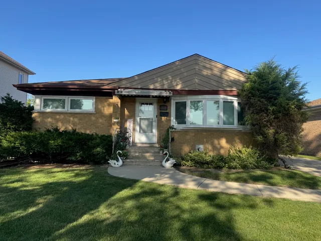 a view of a white house with a big yard and potted plants and trees