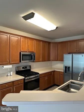 a kitchen with stainless steel appliances kitchen island a stove a refrigerator and a sink