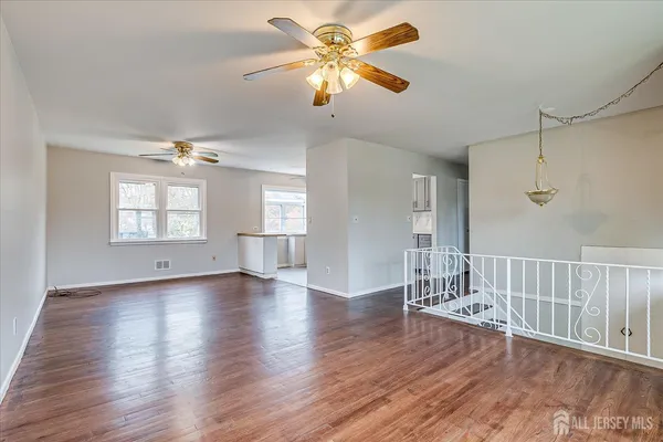 a view of an empty room with window and wooden floor
