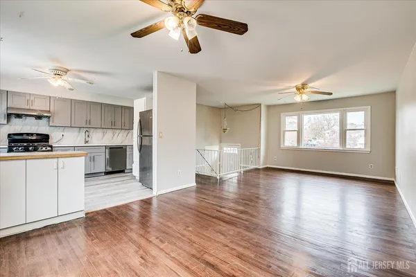 a view of a kitchen with a stove cabinets wooden floor and a ceiling fan