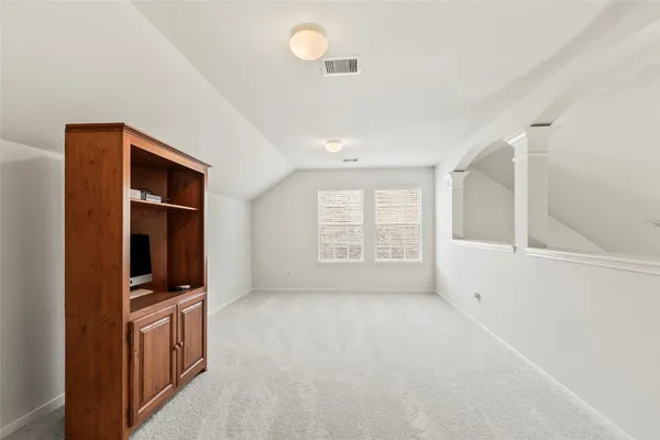 a view of an empty room with a window and a kitchen