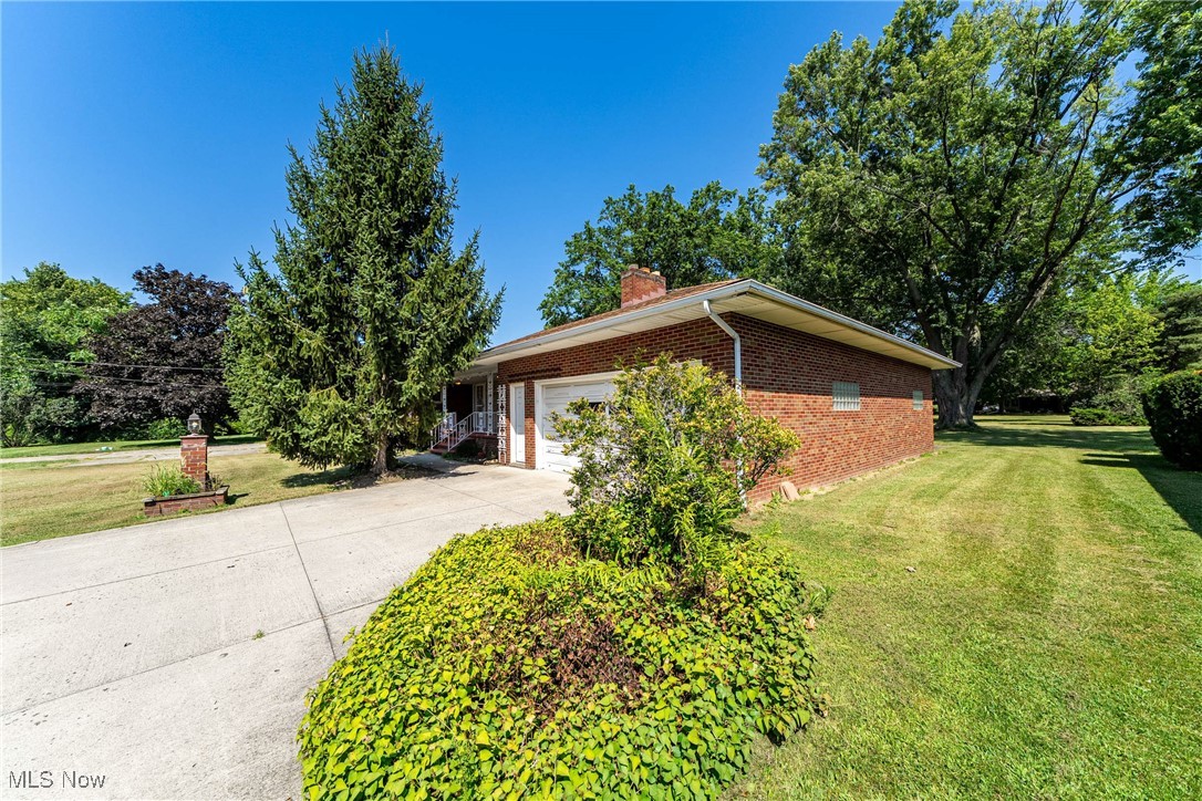 550 Cooper Foster Park Road Lorain, OH 44053 - Photo 3 of 50 View of home's exterior featuring brick siding, a yard, driveway, an attached garage, and a chimney