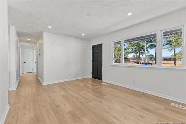 a view of an empty room with wooden floor and windows
