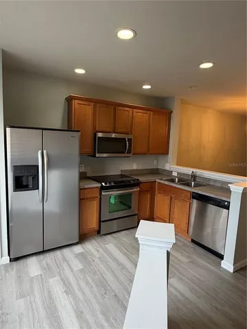 a kitchen with granite countertop a refrigerator and a stove top oven