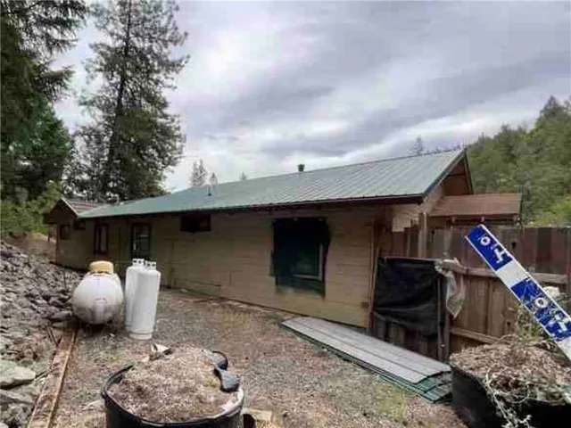 a front view of a house with barbeque grill and wooden fence