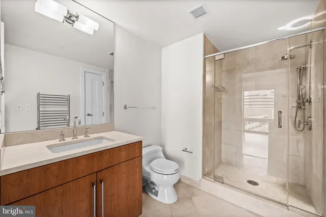 a bathroom with a shower sink vanity mirror and toilet