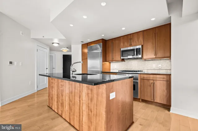 a kitchen with stainless steel appliances kitchen island granite countertop a sink and a microwave